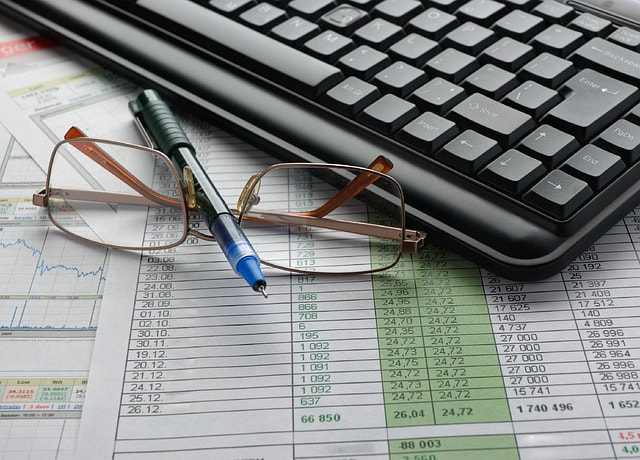financial charts, pen, keyboard and glasses